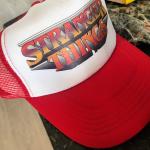 A red and white Stranger Things trucker cap sitting on a kitchen bench
