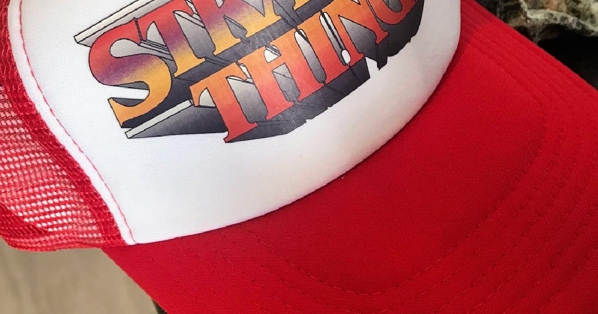 A red and white Stranger Things trucker cap sitting on a kitchen bench